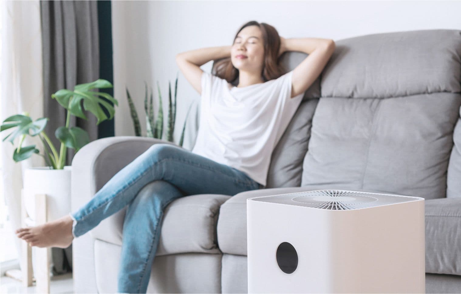 A woman sitting comfortably on the couch enjoying clean cool air with the help of her air purifier 