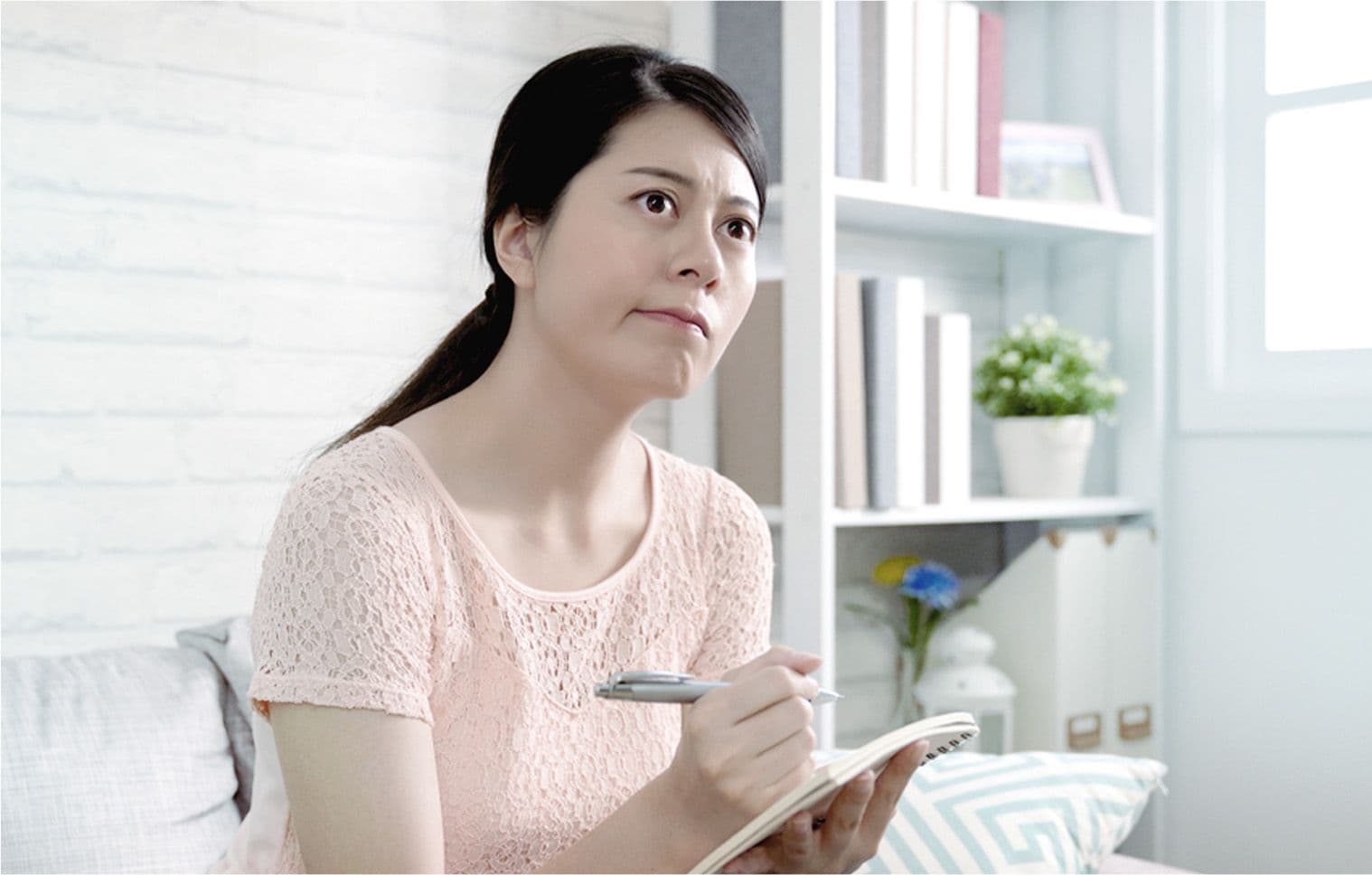 A woman deciding what type of aircon to buy by listing down important factors and details