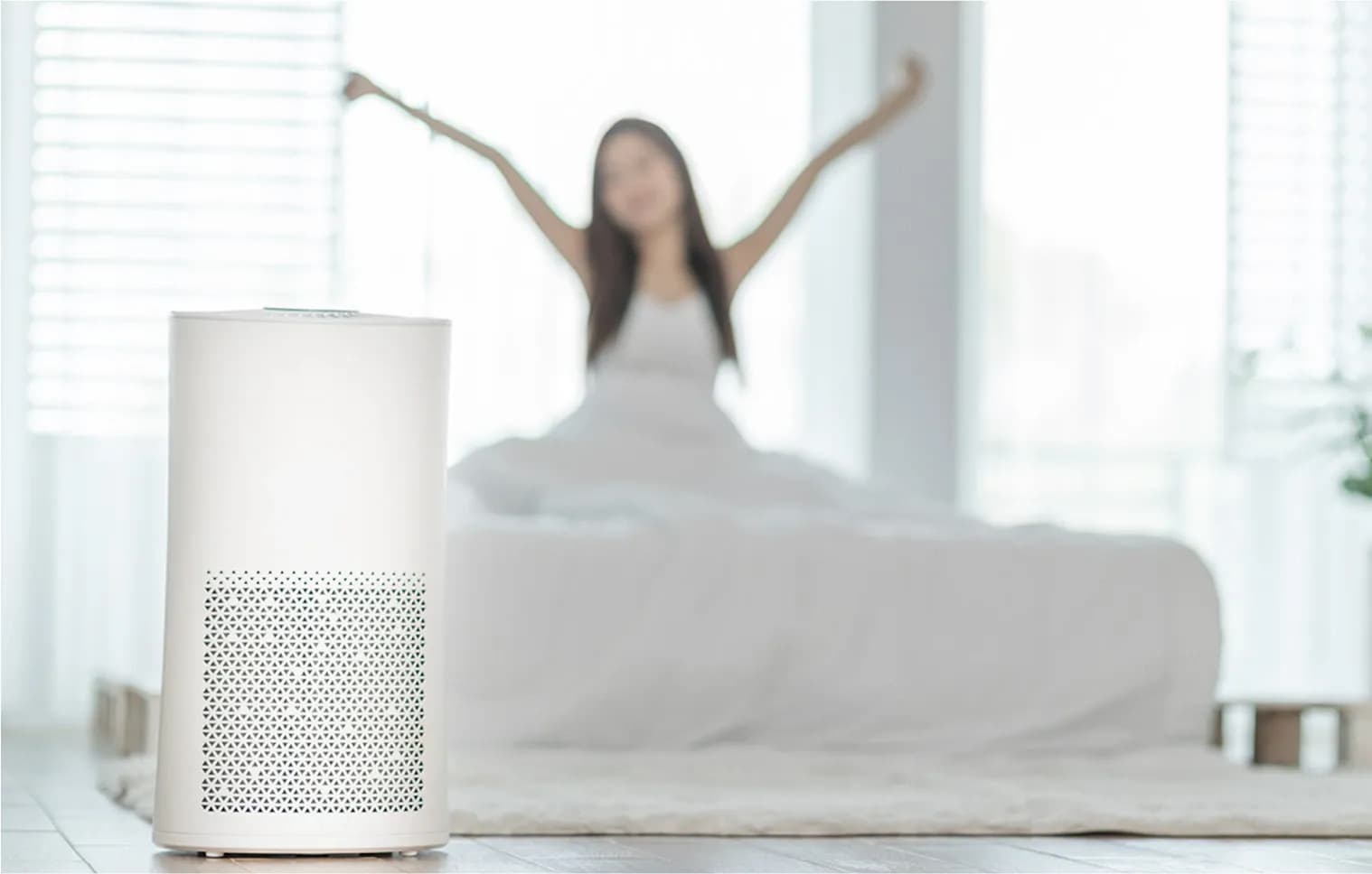 A woman waking up from a restful sleep due to clean indoor air that has been purified by her Carrier HEPA air purifier
