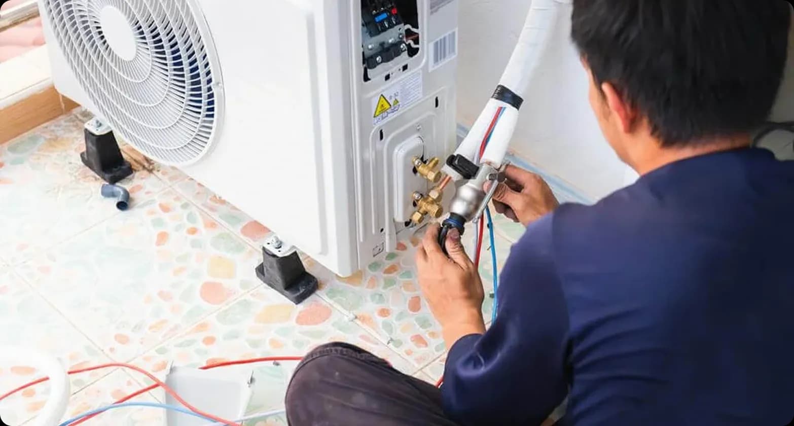 A professional installer carefully setting up a Carrier aircon and outdoor unit