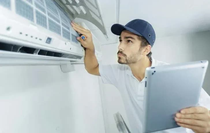 A professional HVAC technician doing regular maintenance and checking the individual components of an aircon