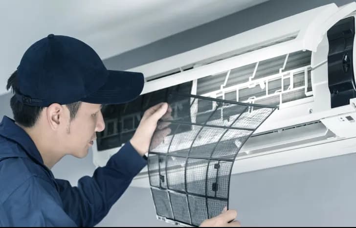 A technician doing aircon cleaning service and maintenance by checking the aircon filters