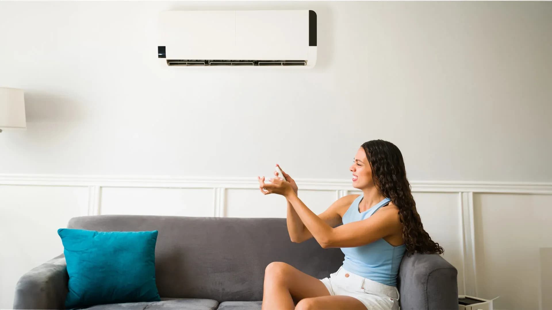 A woman seated on her couch doing some aircon troubleshooting